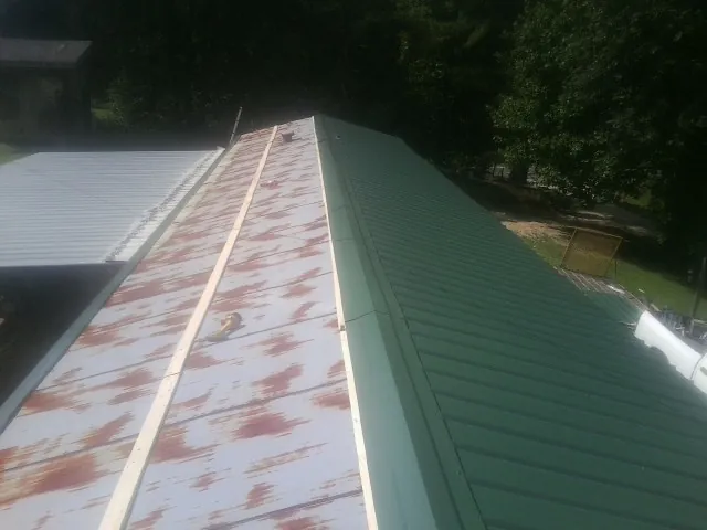 Old rusted panels beside newly installed green metal roofing — Wind Damage Roof Repair by Roofing Brothers in Pacifica