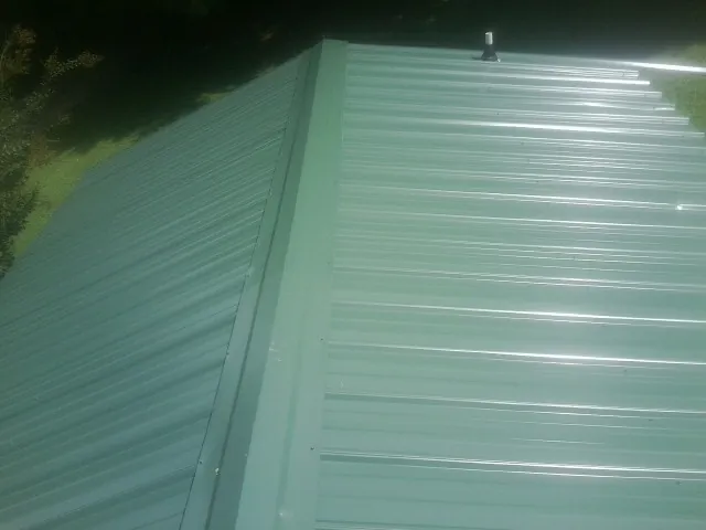 New green metal panels meeting at the ridge of a roof — Flat Roof Repair work by our crew in Pacifica