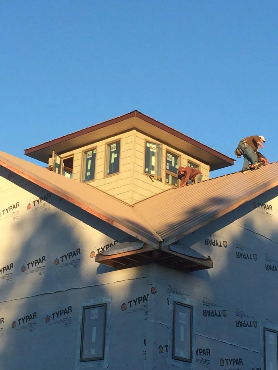 Roofers working around a rooftop cupola on a new metal roof at sunset — Roof Waterproofing in Pacifica by Roofing Brothers